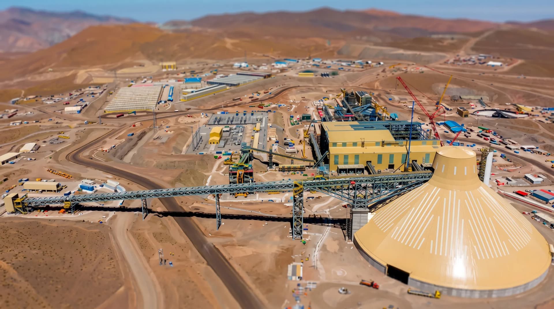 Vista aérea de una faena minera con planta de proceso, correa transportadora y domo de acopio